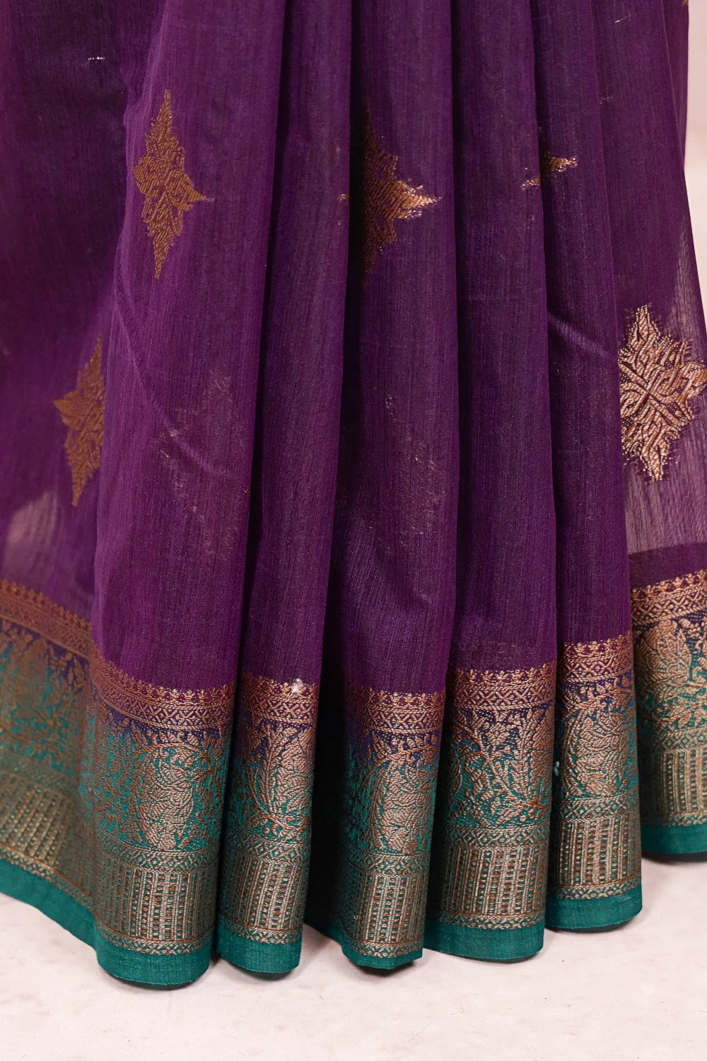 Dark violet semi jute saree fabric spread, paisley zari border