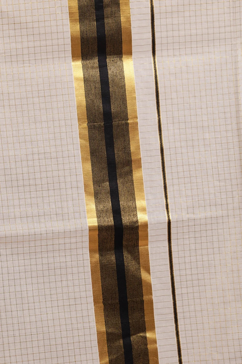 Off white Kerala saree fabric spread, black gold striped border