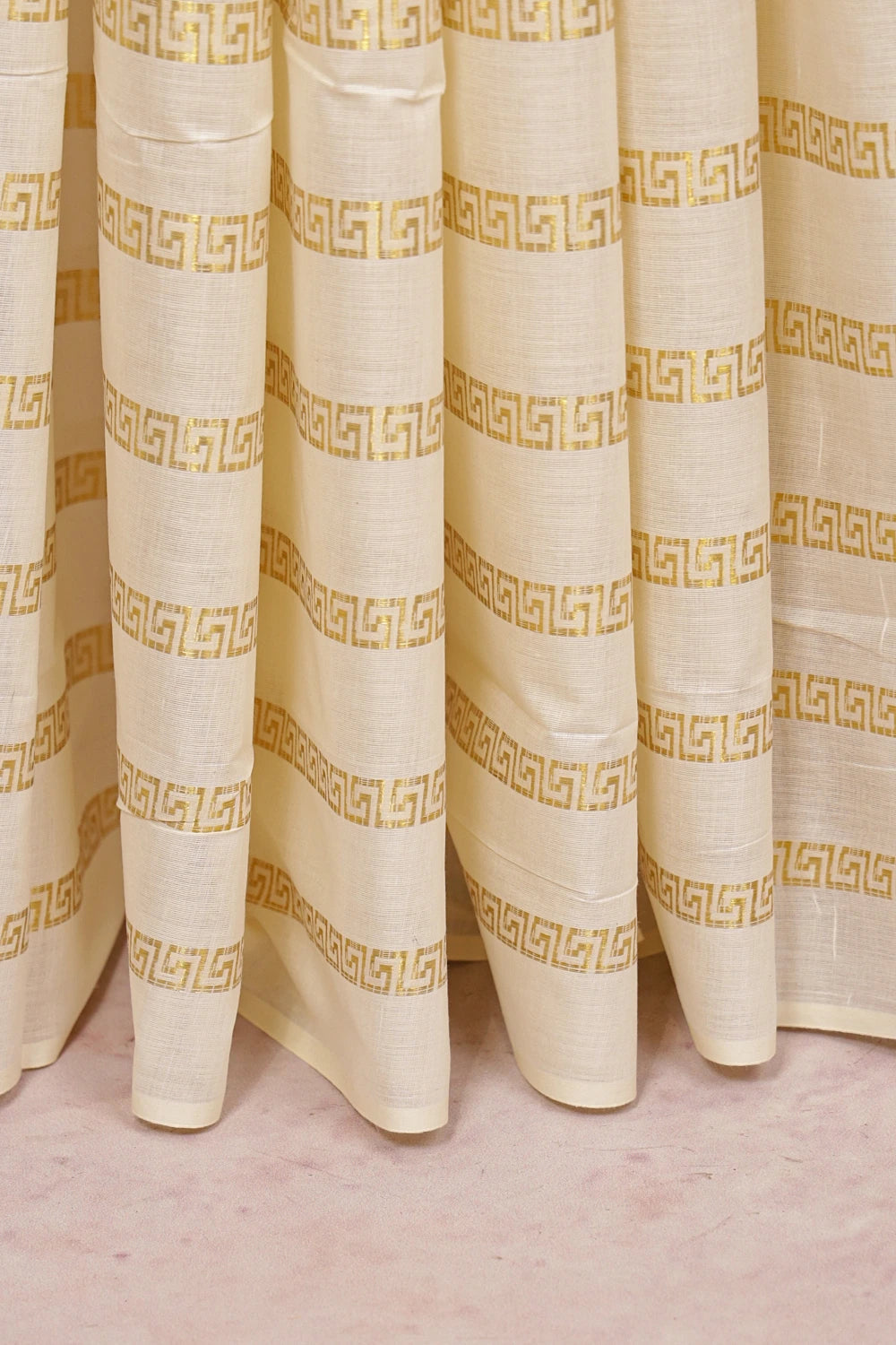 Cream Cotton Kerala Saree fabric spread, golden meander border detail
