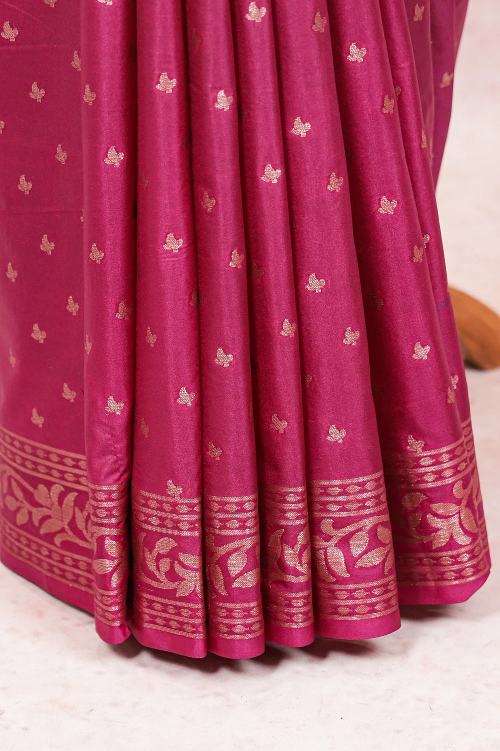 Wine Banarasi saree fabric spread, gold butta and leaf-pattern border